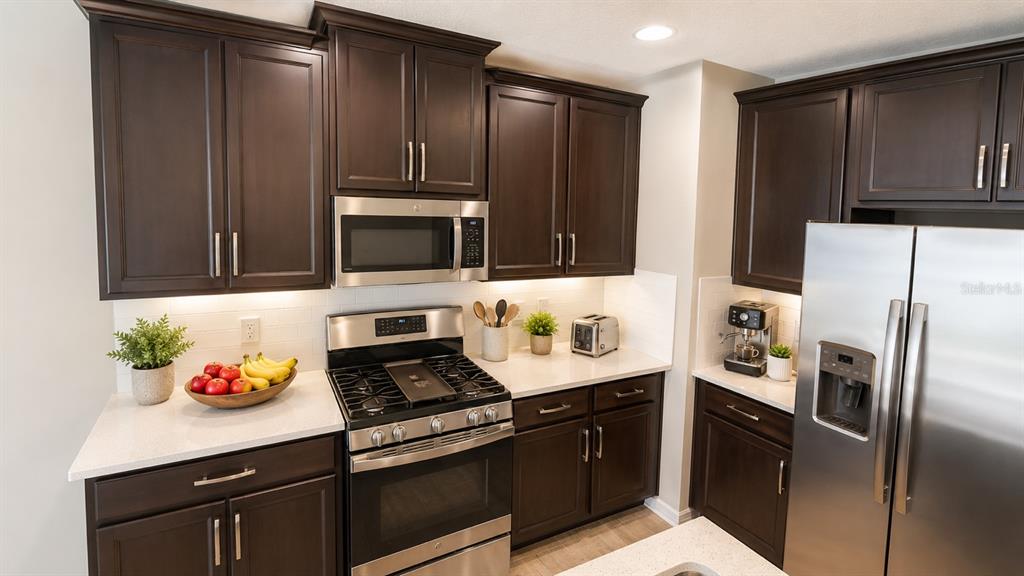 A kitchen features dark wood cabinets, stainless steel appliances, and white countertops — 302 CEDAR BARK LANE, SANFORD, FL