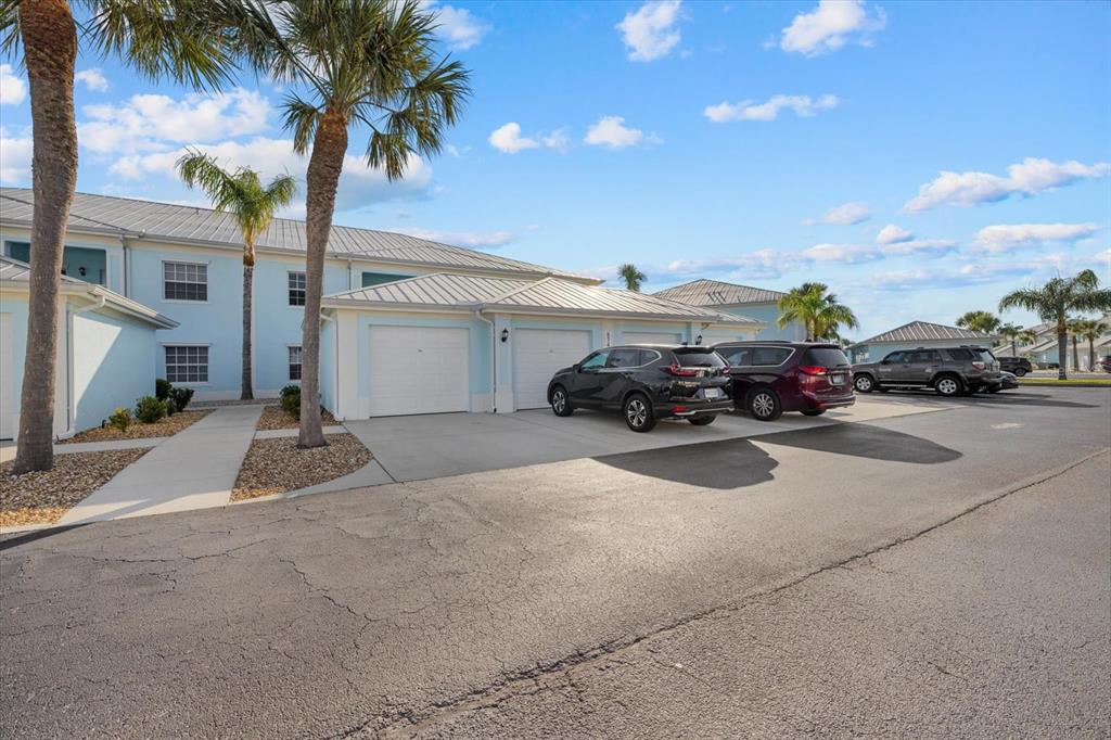 A light blue multi-unit residential building features attached garages and parked cars in front — 5747 SABAL TRACE DRIVE UNIT 203, NORTH PORT, FL