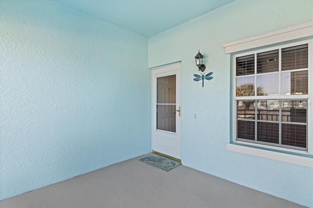 A light blue exterior wall features a white storm door and a window with blinds — 5747 SABAL TRACE DRIVE UNIT 203, NORTH PORT, FL