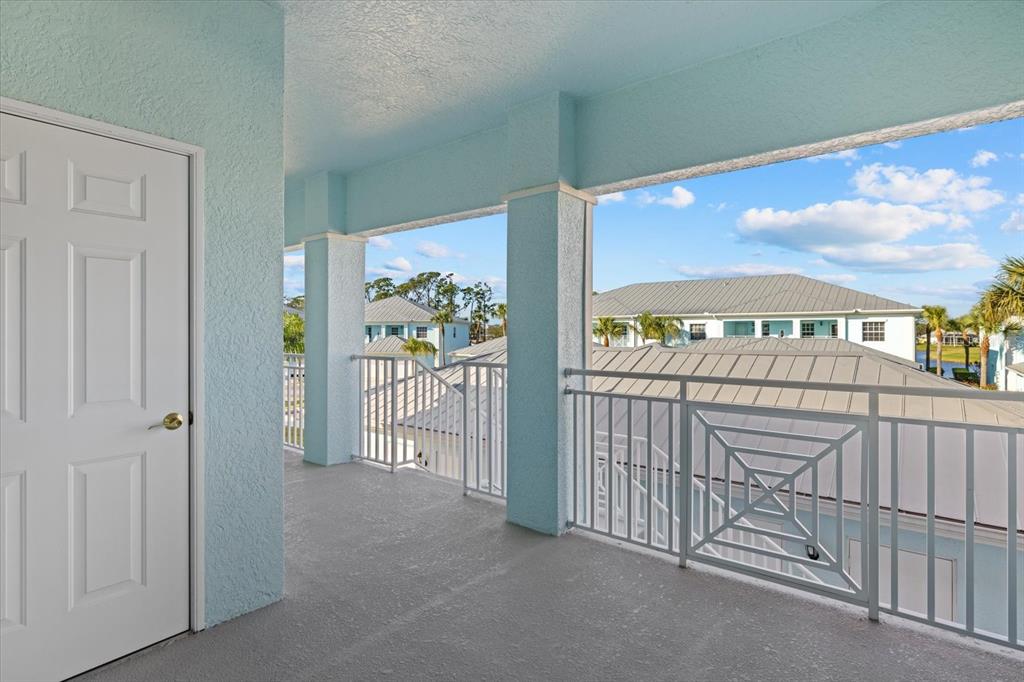 A covered balcony with light blue walls, gray flooring, and white metal railings — 5747 SABAL TRACE DRIVE UNIT 203, NORTH PORT, FL
