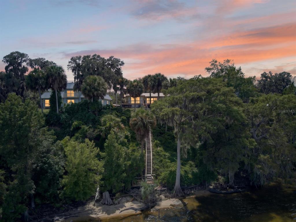 A house sits atop a wooded hill with a long staircase leading down to water — 8445 NE 310TH AVENUE, FORT MC COY, FL