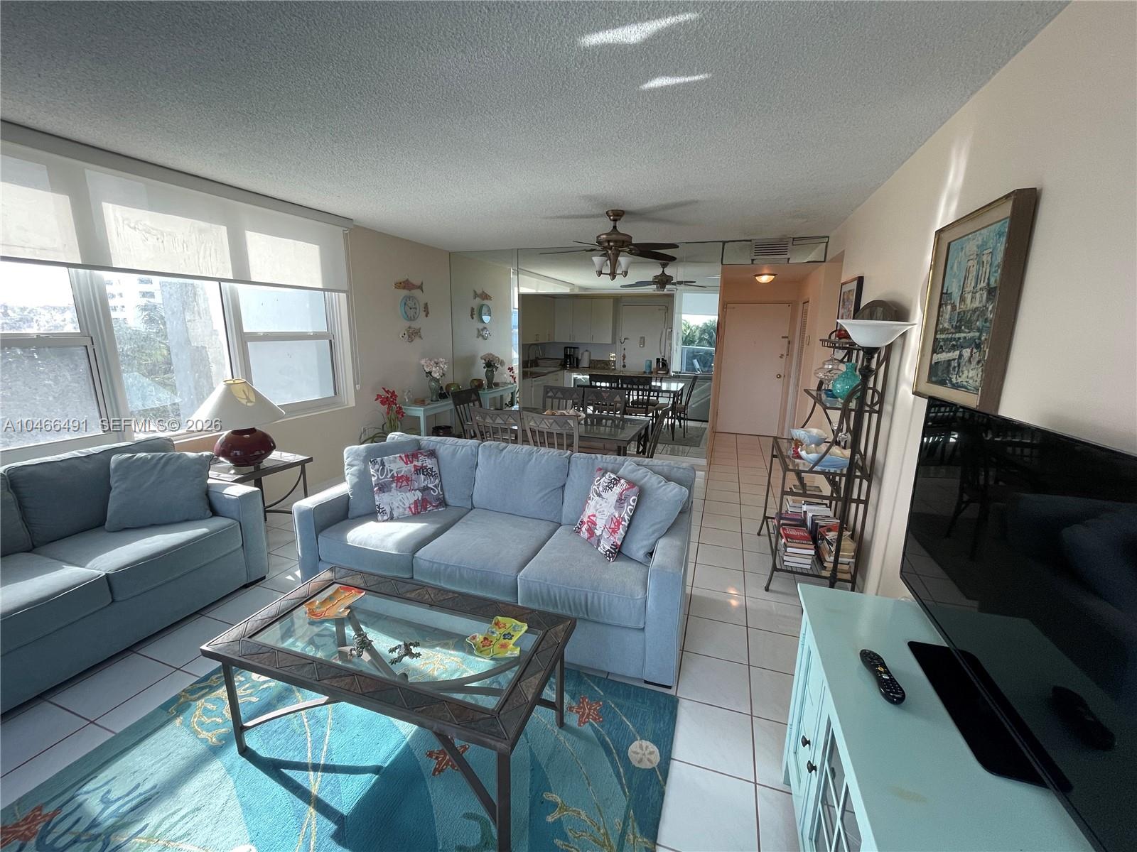 A living room features a blue sofa, glass coffee table, and a mirrored dining area wall — 3505 S OCEAN DR # 421, Hollywood FL 33019, HOLLYWOOD, FL