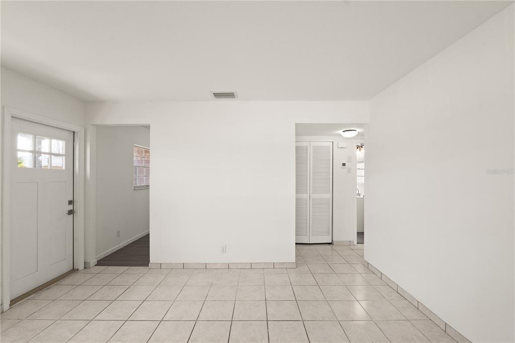 A room with white vertical paneling, wood-plank ceiling, gray flooring, and sliding glass doors — 6206 N LOIS AVENUE, TAMPA, FL