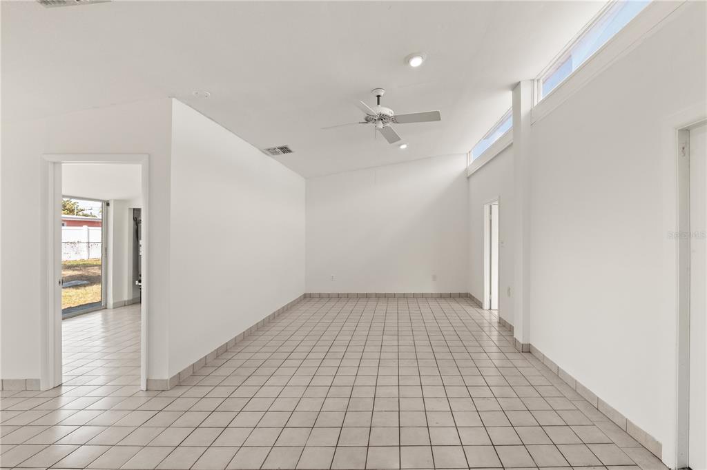 An empty room features white walls, light-colored floor tiles, and a window with vertical blinds — 6206 N LOIS AVENUE, TAMPA, FL