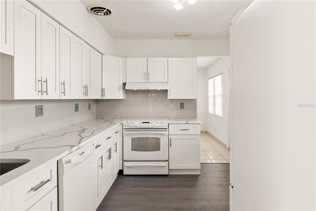 A room with white walls, light-colored tile flooring, a front door, and two arched entryways — 6206 N LOIS AVENUE, TAMPA, FL