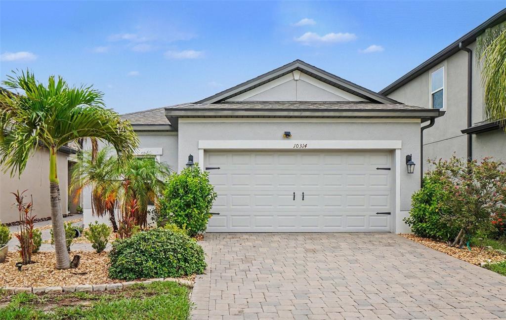 A single-story house with a white garage door, paved driveway, and palm trees in the yard — 10314 BERRYESSA AVE, RIVERVIEW, FL