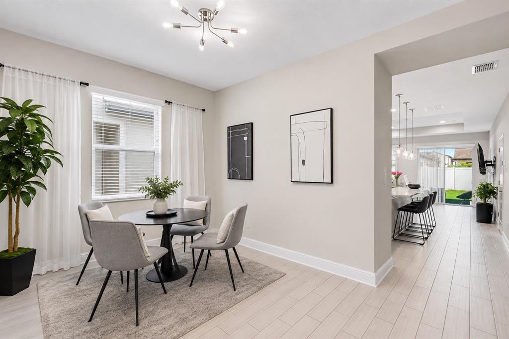A dining area with a round table and chairs sits adjacent to an open kitchen — 10314 BERRYESSA AVE, RIVERVIEW, FL