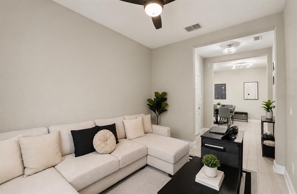 A living room with a beige sectional sofa, a black coffee table, and a dining area — 10314 BERRYESSA AVE, RIVERVIEW, FL