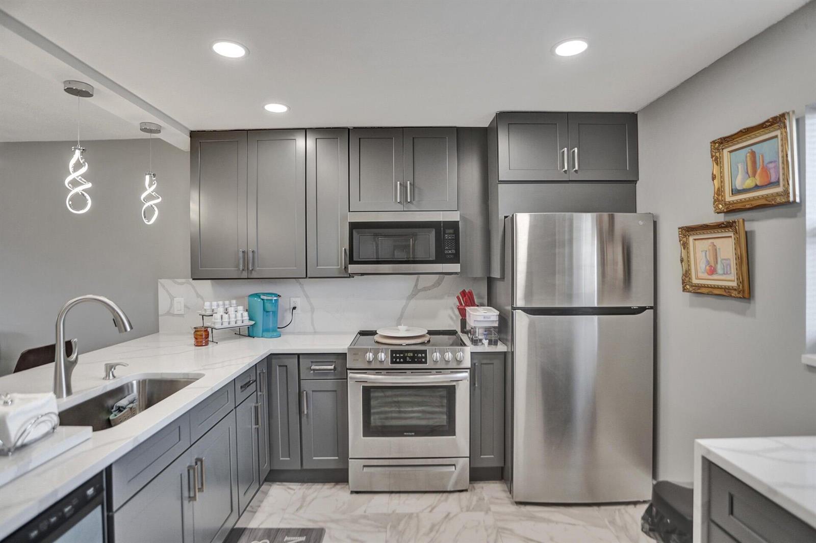 A kitchen features gray cabinets, stainless steel appliances, white countertops, and a marble-patterned backsplash — 130 NE 26th Avenue # 3070, Boynton Beach FL 33435, BOYNTON BEACH, FL