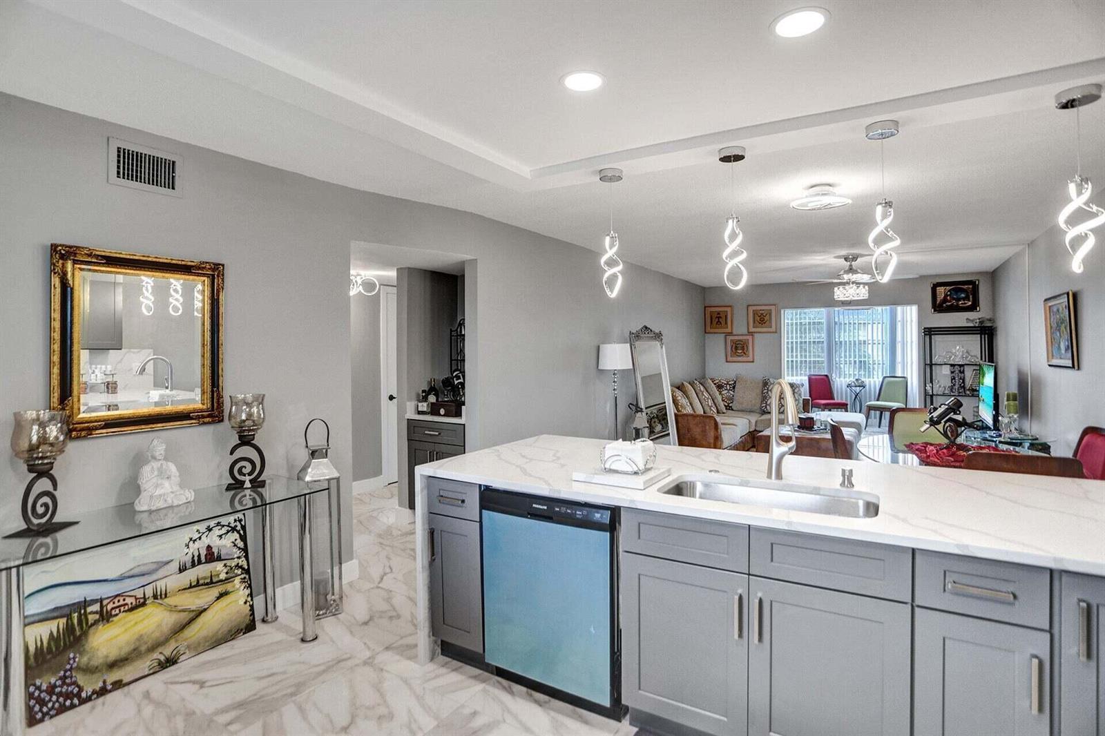 A kitchen island with a sink and dishwasher overlooks a living area with gray walls — 130 NE 26th Avenue # 3070, Boynton Beach FL 33435, BOYNTON BEACH, FL