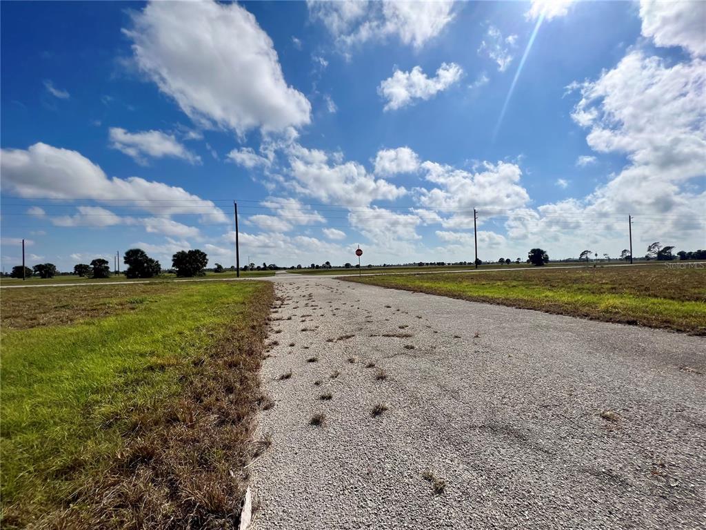 A gravel road leads toward a stop sign in a flat, grassy, open field — 4 COTTONWOOD COURT, PLACIDA, FL