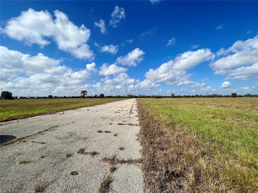 A paved road stretches through a flat, grassy field under a bright, cloudy blue sky — 4 COTTONWOOD COURT, PLACIDA, FL