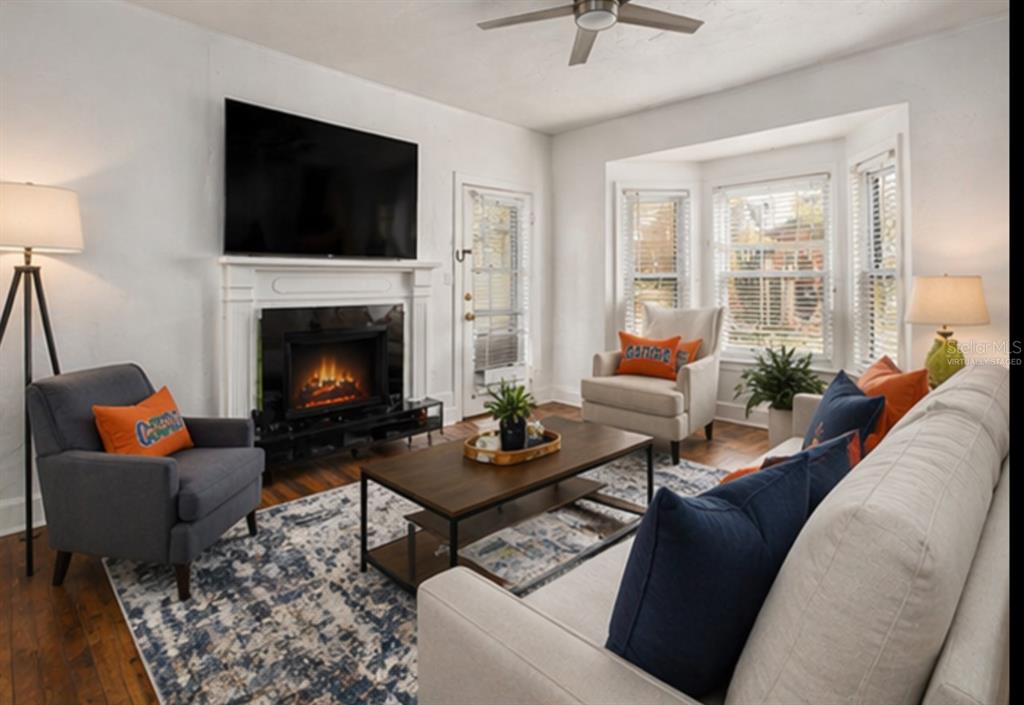 A living room features a fireplace with a mounted television, seating, and a bay window — 1254 SW 9TH ROAD, GAINESVILLE, FL