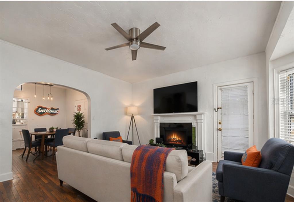 A living room with a fireplace, television, ceiling fan, and an adjacent dining area — 1254 SW 9TH ROAD, GAINESVILLE, FL