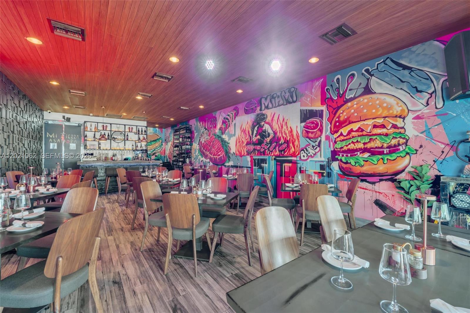 A restaurant dining room features wood-paneled ceilings, wood-look flooring, and a large, colorful burger mural — 10548 SW 8, Miami FL 33174, MIAMI, FL