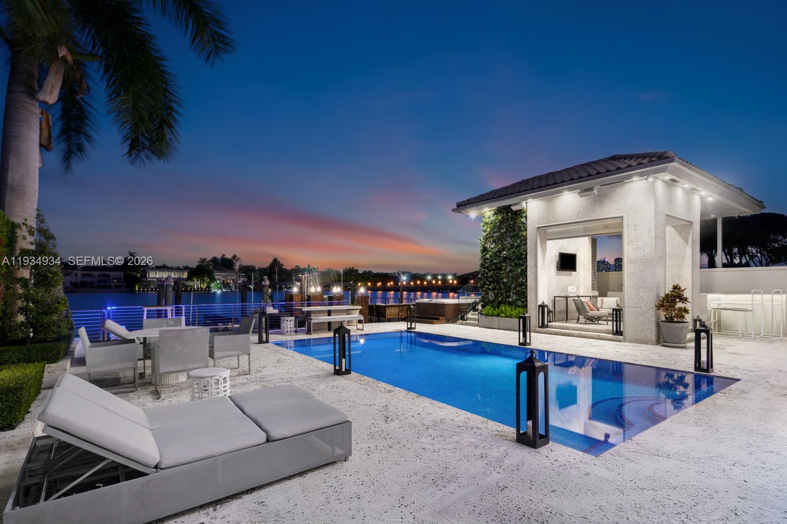 A swimming pool sits on a stone patio next to a covered cabana at dusk — 176 S Hibiscus Drive, Miami Beach FL 33139, MIAMI BEACH, FL