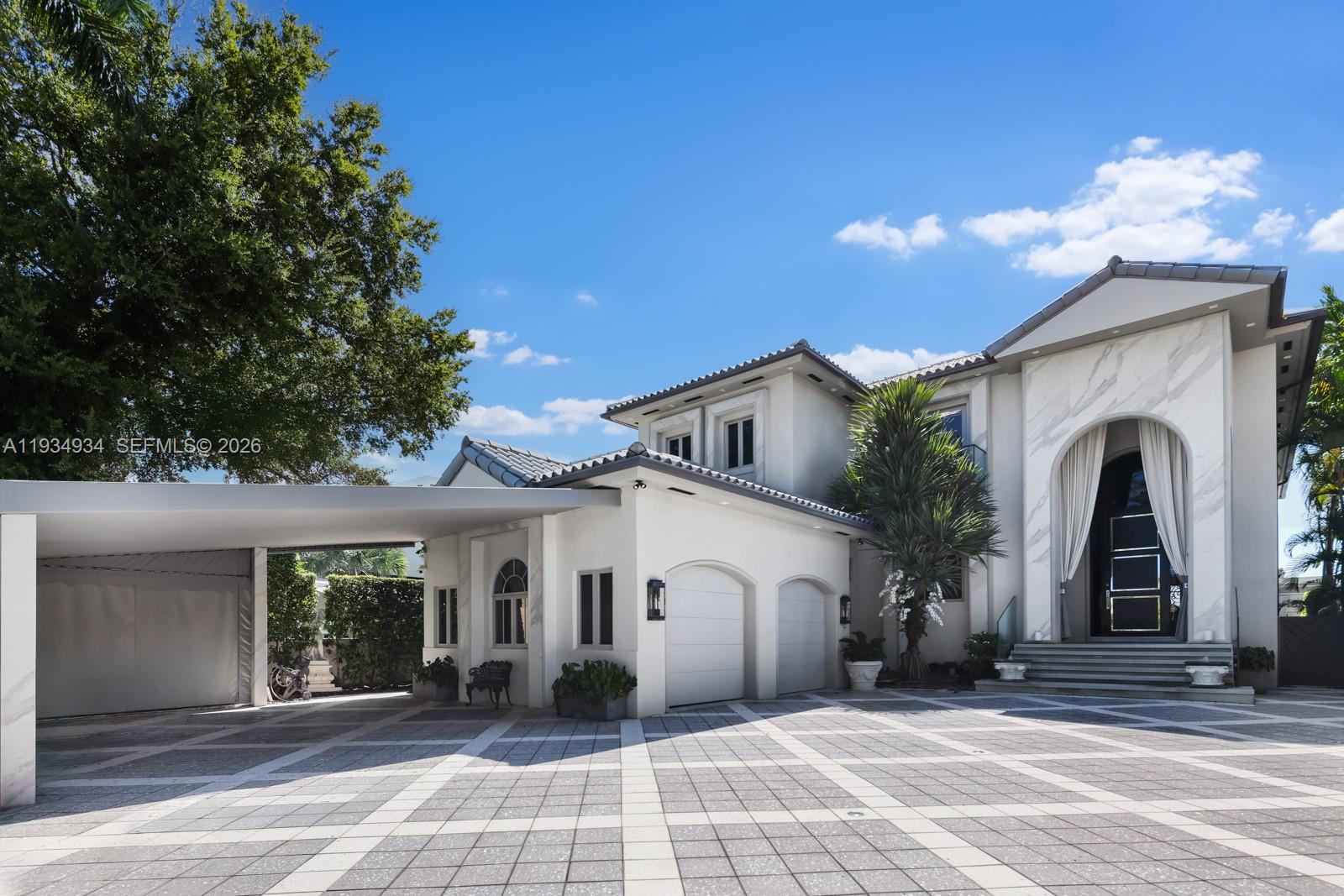A two-story house features a paved driveway, a carport, and a grand arched entryway — 176 S Hibiscus Drive, Miami Beach FL 33139, MIAMI BEACH, FL