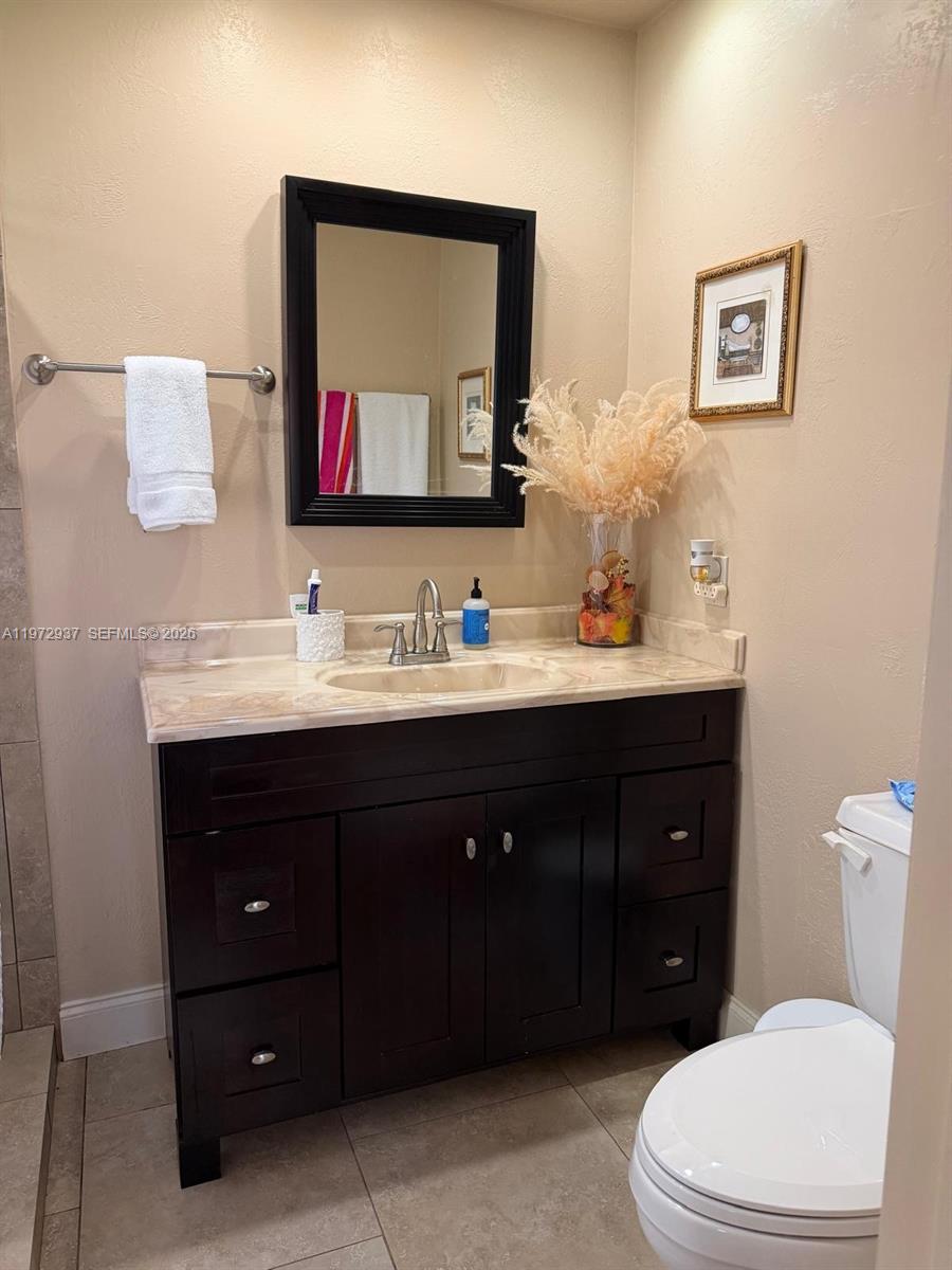 A bathroom features a dark wood vanity with a stone countertop and a black-framed mirror — 1350 NW 96th St # 2, Miami FL 33147, MIAMI, FL