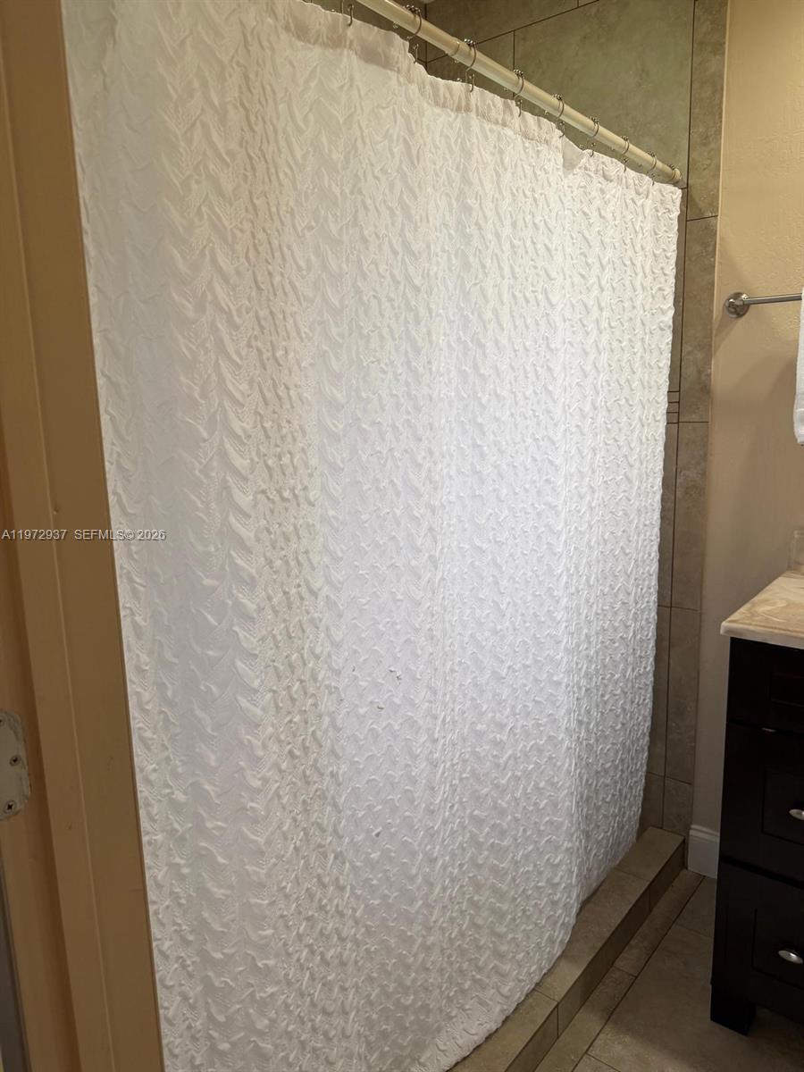 A white textured shower curtain hangs on a rod in a tiled bathroom — 1350 NW 96th St # 2, Miami FL 33147, MIAMI, FL