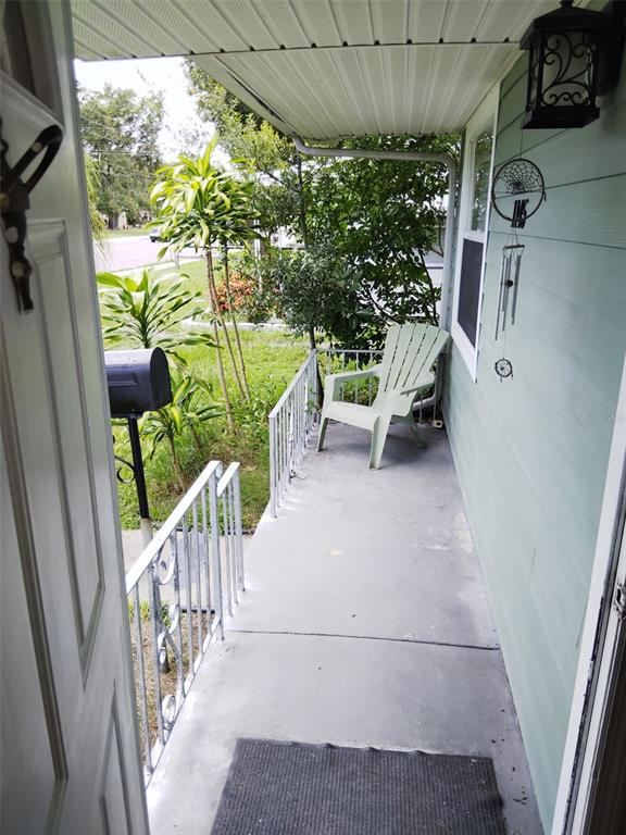 A view from a doorway looking out onto a covered concrete porch with a chair — 1145 54TH AVENUE N, ST PETERSBURG, FL