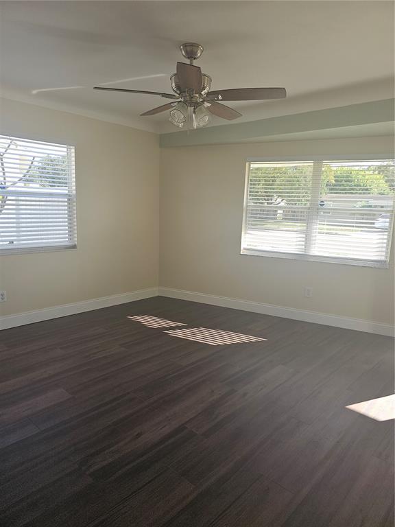 An empty room with dark wood-look flooring, cream walls, two windows with blinds, and a ceiling fan — 1145 54TH AVENUE N, ST PETERSBURG, FL