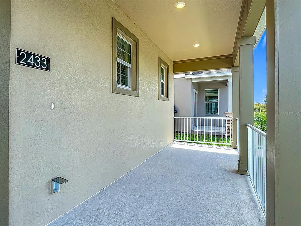 A covered balcony features a concrete floor, white railings, and two recessed ceiling lights — 2433 SPRING TUNE ALLEY, KISSIMMEE, FL