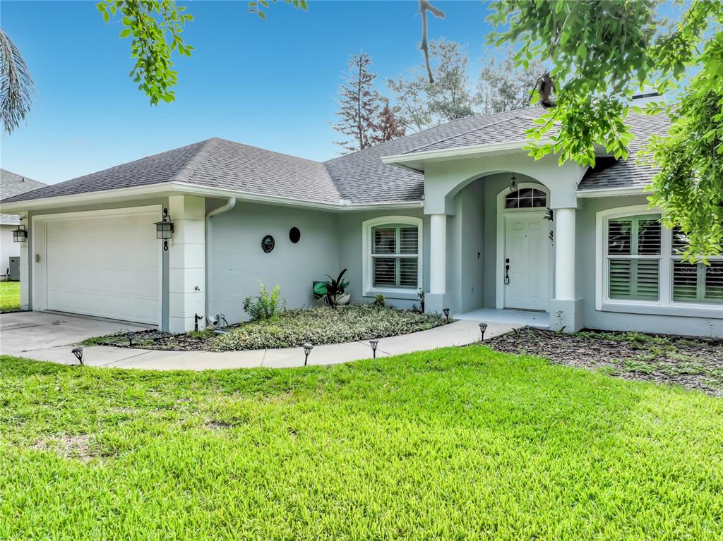 A single-story house with a light gray exterior, a two-car garage, and a covered entryway — 9418 MEADOW CREST LANE, CLERMONT, FL