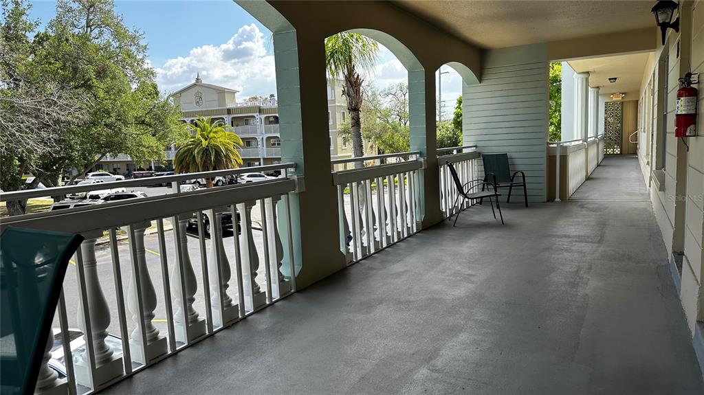 A covered outdoor balcony features a white railing, concrete flooring, and views of a parking lot — 2330 ECUADORIAN WAY UNIT 32, CLEARWATER, FL