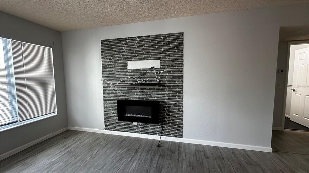 A living room features gray wood-look flooring, light walls, and a tiled fireplace accent wall — 2330 ECUADORIAN WAY UNIT 32, CLEARWATER, FL