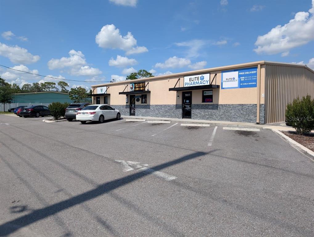 A single-story commercial building with a parking lot in front and two storefronts — 7011 N MANHATTAN AVENUE, TAMPA, FL