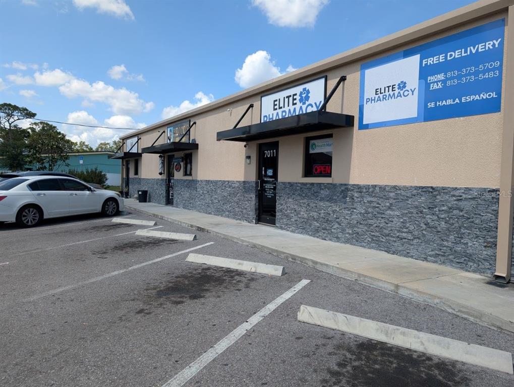 Exterior view of a commercial building featuring Elite Pharmacy with parking spaces in front — 7011 N MANHATTAN AVENUE, TAMPA, FL