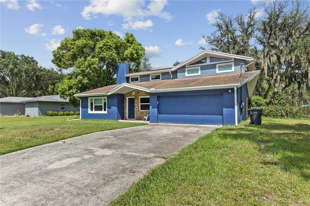 A blue two-story house with a stone accent wall and a concrete driveway — 4734 MONTEREY DRIVE, WINTER HAVEN, FL