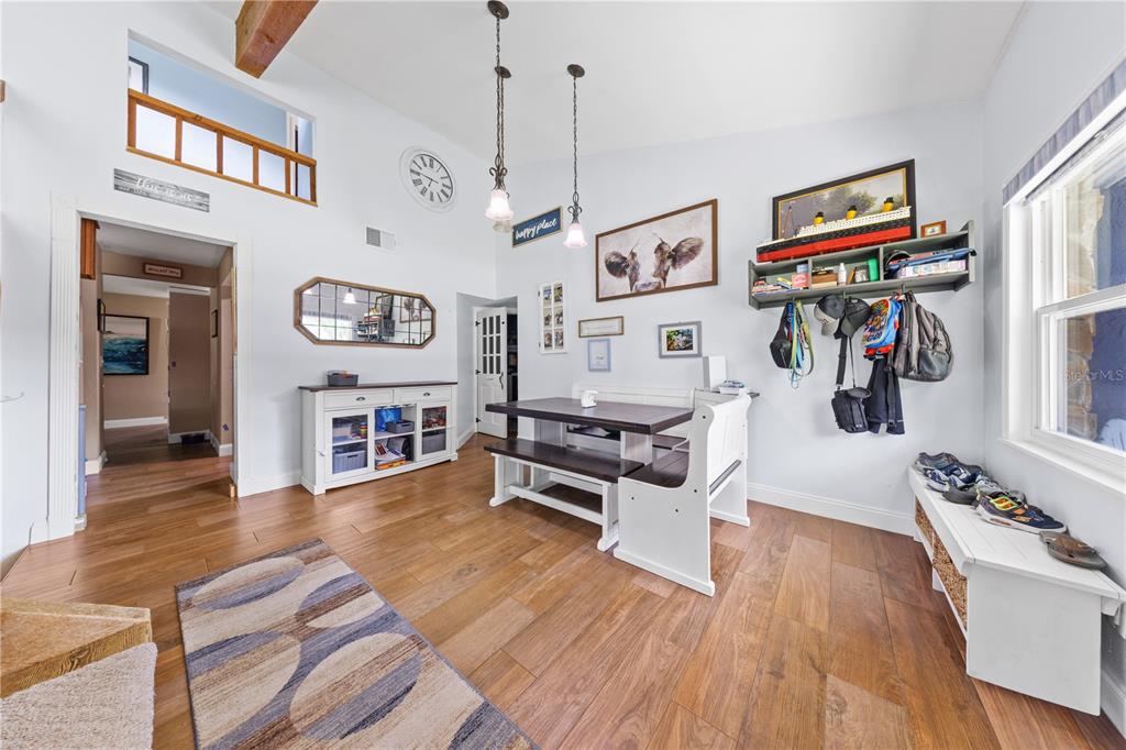 A dining area features wood flooring, a white bench table set, and a wall-mounted storage shelf — 4734 MONTEREY DRIVE, WINTER HAVEN, FL