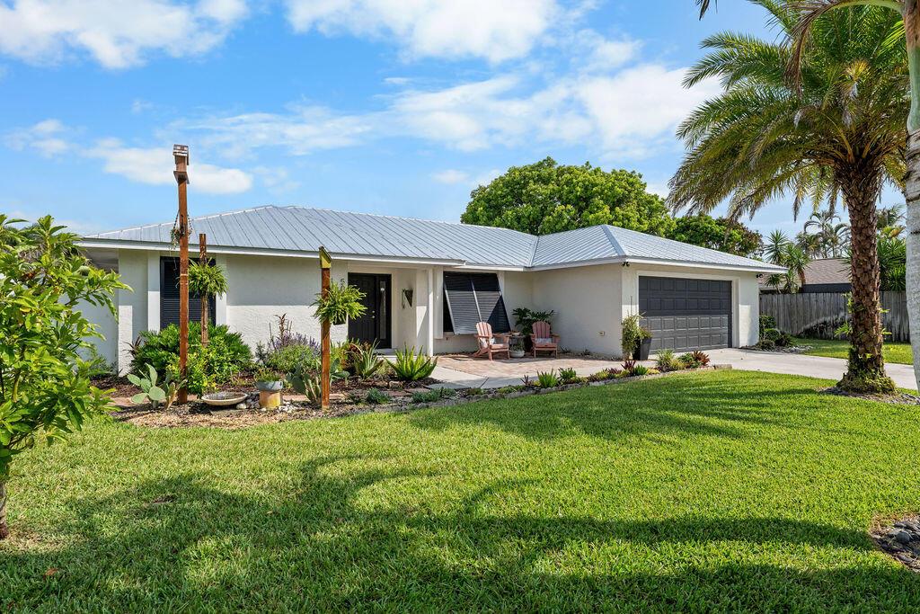 A single-story house with a metal roof, a two-car garage, and a front patio — 5068 SE Major Way, Stuart FL 34997, STUART, FL