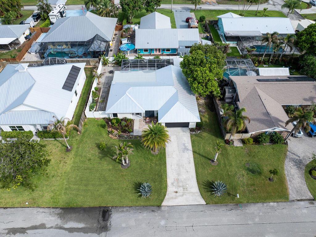 An aerial view shows a residential neighborhood with several houses featuring metal roofs and pools — 5068 SE Major Way, Stuart FL 34997, STUART, FL