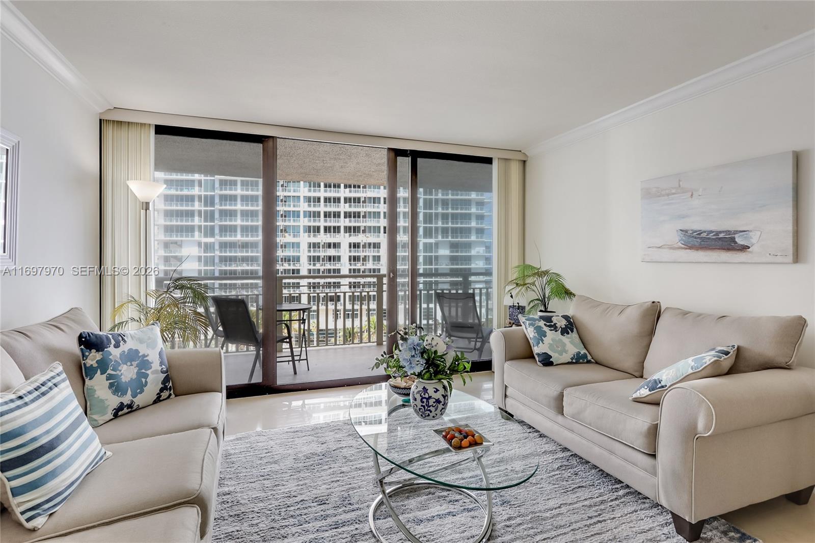 A living room features two beige sofas, a glass coffee table, and a balcony view — 3000 N Ocean Dr # 10B, Riviera Beach FL 33404, RIVIERA BEACH, FL