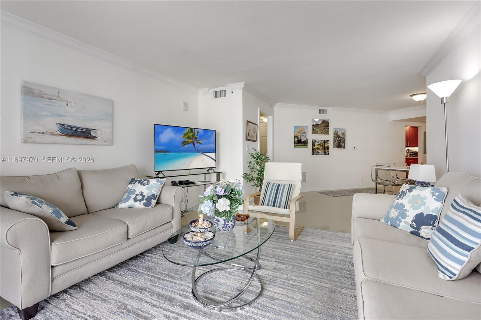 A living room features two beige sofas, a glass coffee table, and a television — 3000 N Ocean Dr # 10B, Riviera Beach FL 33404, RIVIERA BEACH, FL