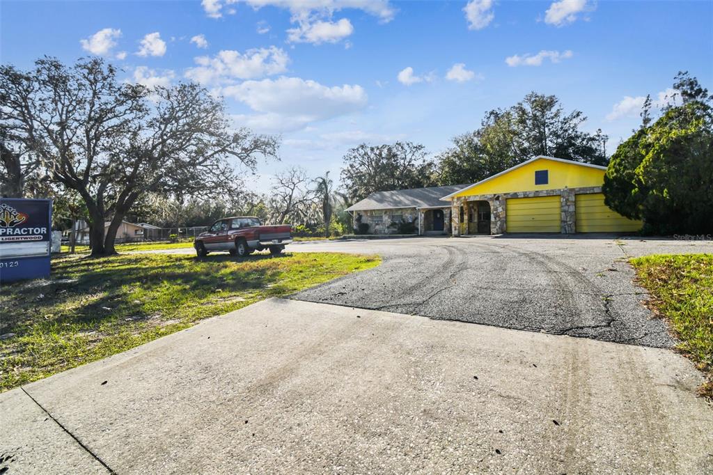 A single-story house with a yellow garage and a large driveway sits under a blue sky — 10129 LITTLE ROAD, NEW PORT RICHEY, FL