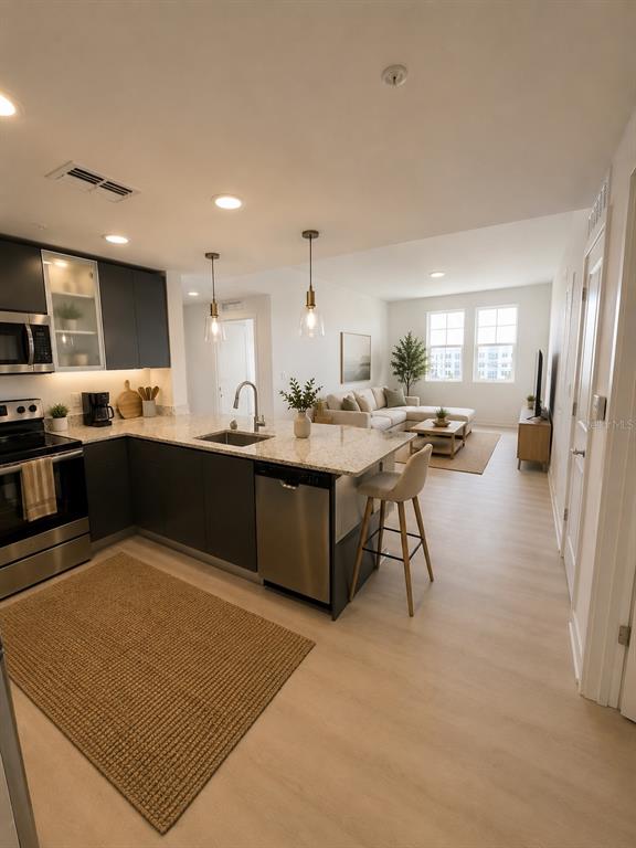 A modern kitchen with dark cabinets and granite countertops opens into a bright living room — 5579 MILLENIA PARK BOULEVARD UNIT 309, ORLANDO, FL