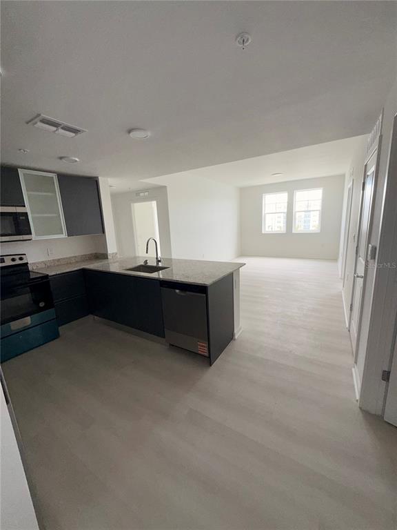 A kitchen with dark cabinets and a granite island opens into a spacious living area — 5579 MILLENIA PARK BOULEVARD UNIT 309, ORLANDO, FL