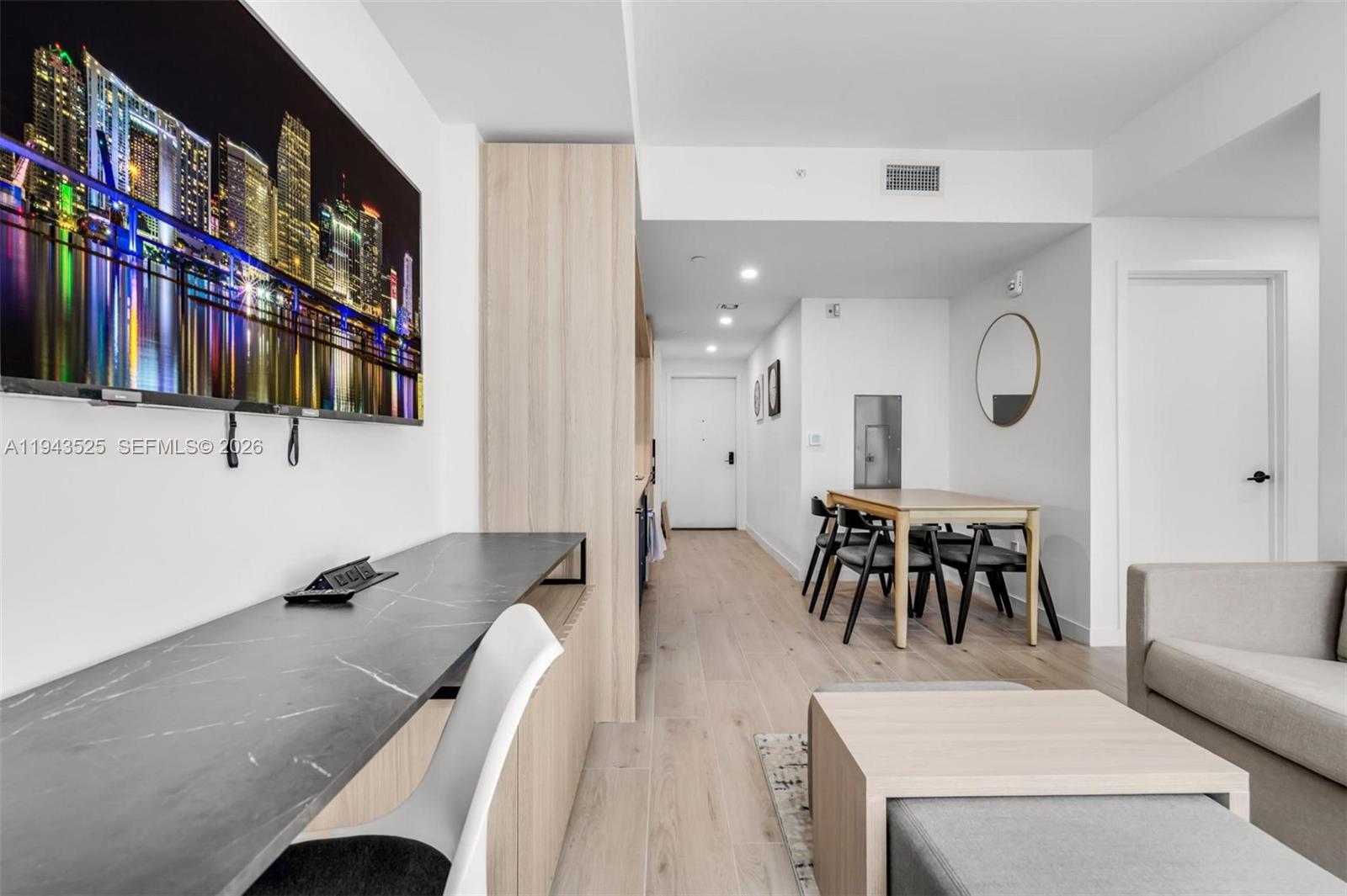 A modern living area features a wall-mounted television, a desk, and a dining table — 225 N Miami Ave # 1005, Miami FL 33128, MIAMI, FL