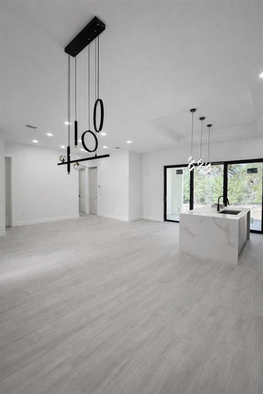 A modern open-concept kitchen and living area features light wood-look flooring and two pendant lights — 1105 CORNELIUS BOULEVARD, PORT CHARLOTTE, FL