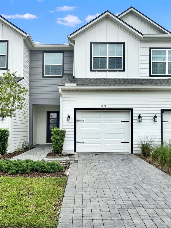 A two-story townhouse exterior features white horizontal siding, a gray shingled roof, and a garage — 1471 BROOKDALE COURT, OVIEDO, FL