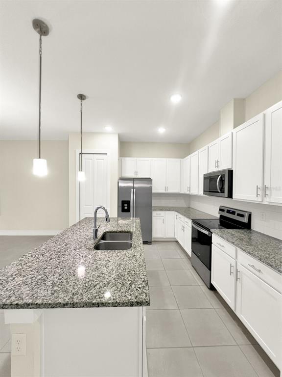 A kitchen features white cabinets, granite countertops, a stainless steel refrigerator, and a center island — 1471 BROOKDALE COURT, OVIEDO, FL