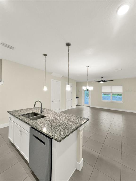 A kitchen island with a granite countertop and stainless steel dishwasher faces an open living area — 1471 BROOKDALE COURT, OVIEDO, FL
