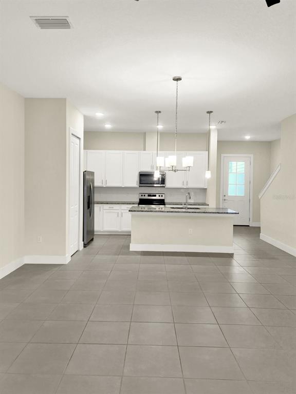 A kitchen with white cabinets, stainless steel appliances, and a central island with gray tile flooring — 1471 BROOKDALE COURT, OVIEDO, FL