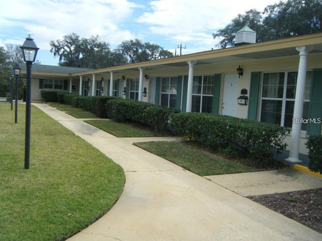 A single-story building with a covered walkway, white columns, and green shutters — 109 PERKINS STREET UNIT 9, LEESBURG, FL