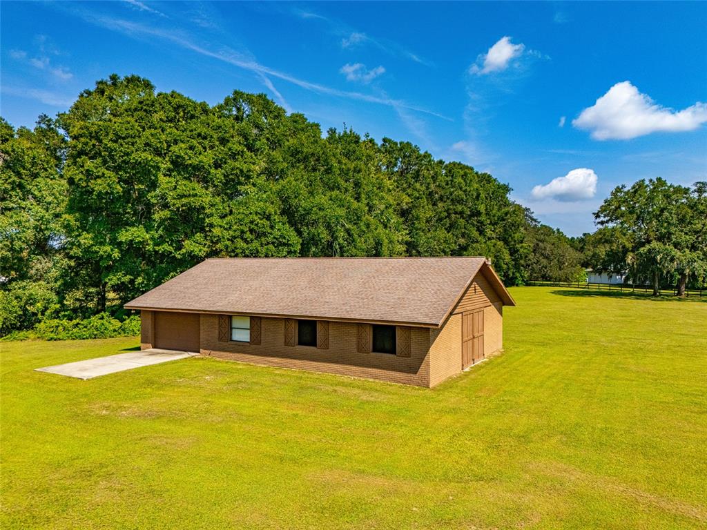 A single-story brick house with a large tree in the front yard and attached garage — 9901 SW 67TH TERRACE, OCALA, FL