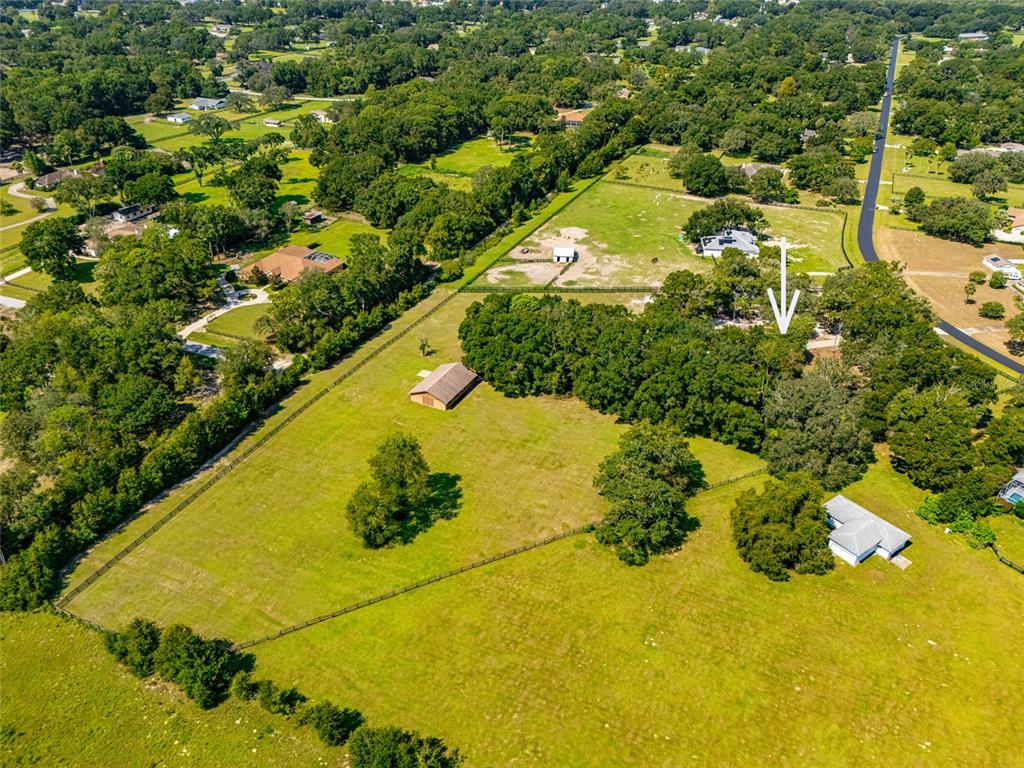 A brown barn sits in the middle of a large, grassy field surrounded by trees — 9901 SW 67TH TERRACE, OCALA, FL