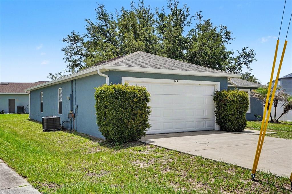 A blue detached garage with a white door and two large bushes in front — 449 DANUBE DRIVE, KISSIMMEE, FL